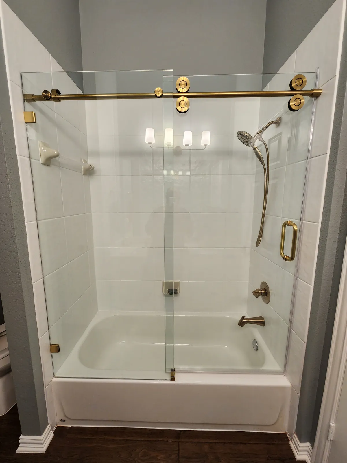 Sliding glass tub door on a brass roller bar with a brass pull